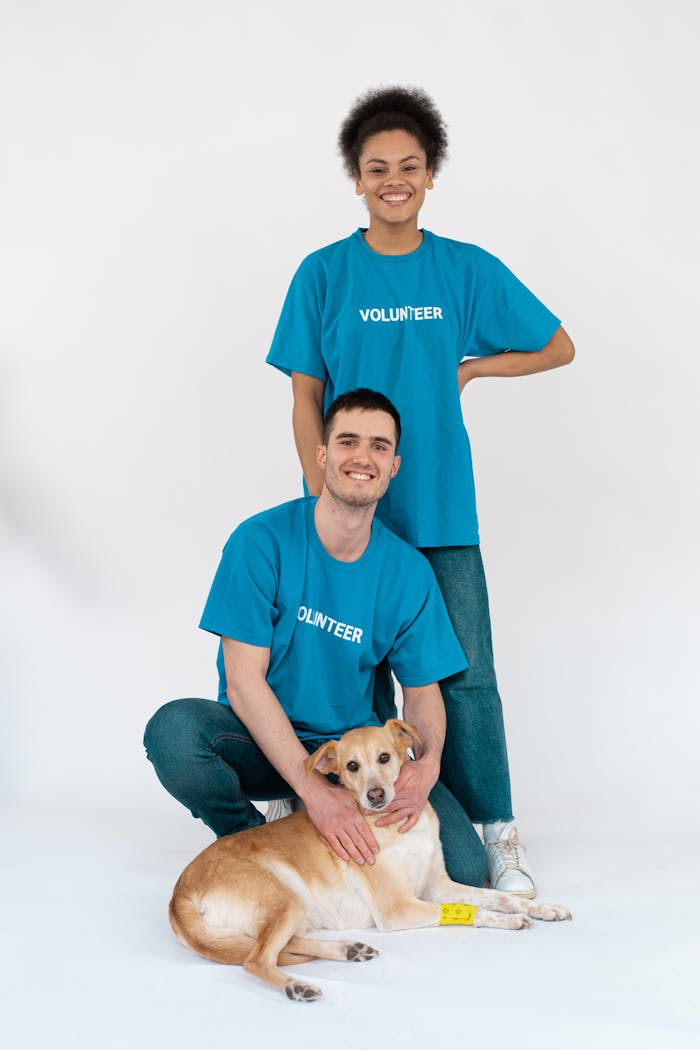 menu-08 Two volunteers pose happily with a cute dog during a studio shoot to promote pet adoption.